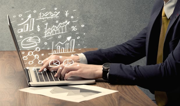 Sales person in suit using a laptop to calculate pie chart and exponential growth statistics on office desk concept