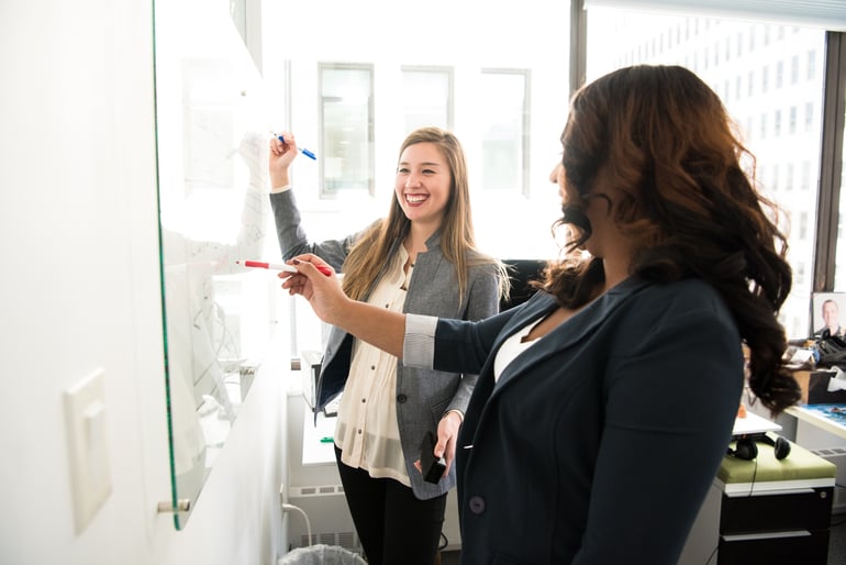 two coworkers writing down notes